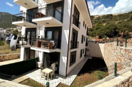 a white apartment building with a balcony and a chair at Ozy Apart / Can Andifli in Kas