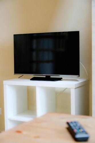 a television on a white stand with a remote control at Agriturismo Cascina della Fontana in Lodi