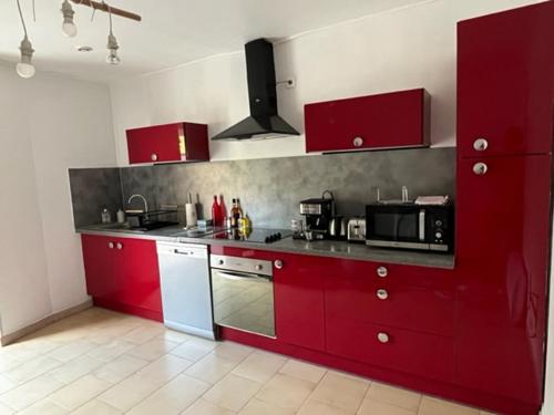 une cuisine avec des armoires rouges et un appareil blanc dans l'établissement Gîte tout confort en Cévennes 3 étoiles, à Saint-Martin-de-Valgalgues