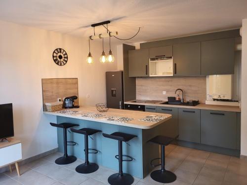 une cuisine avec un îlot et des tabourets de bar dans l'établissement RESIDENCE LE DOMAINE DE MARTHIAS, au Teich