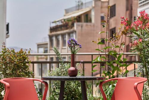 a table with a vase on it with three chairs at DWELL - Elegant City Stay in Athens
