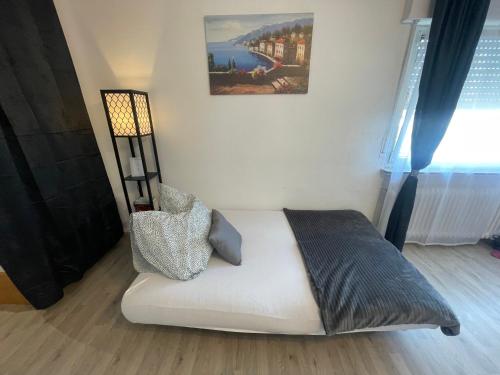 a white bed in a room with a painting on the wall at Perfekte 1,5 Wohnung Zentral in Leonberg gegenüber Einkaufzentrum in Leonberg