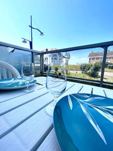 uma mesa de madeira com 2 copos de vinho na varanda em Studio à 50m à pieds de la plage em Neufchâtel-Hardelot