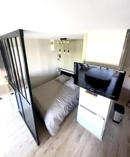 um pequeno quarto com uma cama e uma televisão de ecrã plano em Studio à 50m à pieds de la plage em Neufchâtel-Hardelot
