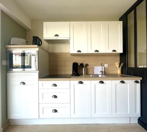 une cuisine avec des armoires blanches et un évier dans l'établissement Studio à 50m à pieds de la plage, à Neufchâtel-Hardelot