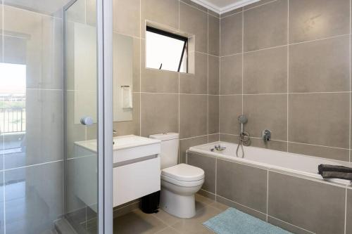 a bathroom with a toilet and a tub and a sink at Gorgeous Ballito One Bedroom apartment in Ballito