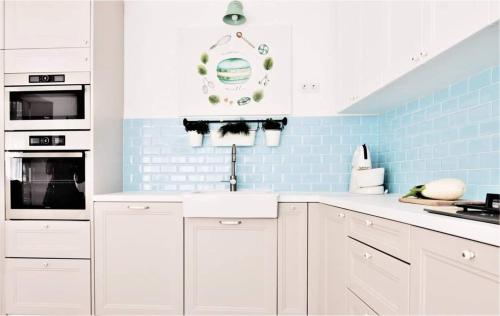 a kitchen with white cabinets and blue tiles at Casa Good Vibes in Târgu-Mureş