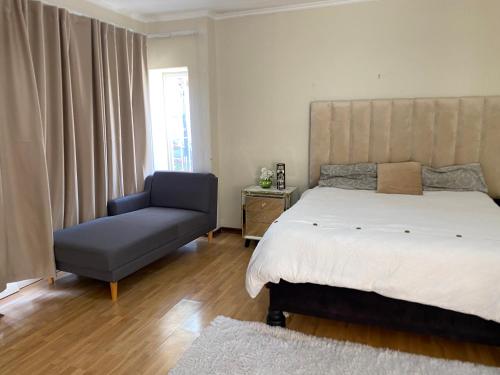 a bedroom with a large bed and a chair at Siena Sun Guesthouse Rooms and Breakfast Option in Midrand