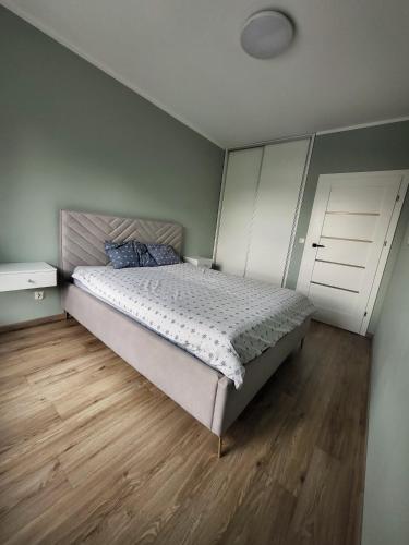 een slaapkamer met een bed en een houten vloer bij Apartament w Parku nad Kanałem in Bydgoszcz