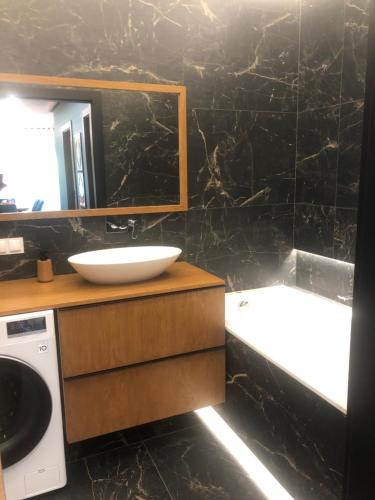 a bathroom with a sink and a tub and a mirror at Solankowa Aleja Apartament Rodzinny in Inowrocław