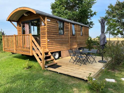 a wooden cabin with a porch and a table on a deck at DOMAINE DES GALINACES ROULOTTE LA ROUSSETTE 2-4P in Marigny-lès-Reullée