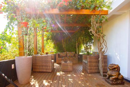 una terraza con sillas de mimbre y una pérgola con plantas en Suítes Jurerê Internacional, en Florianópolis