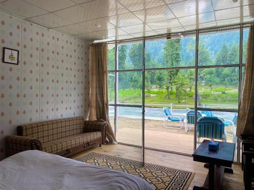 a bedroom with a couch and a large window at Valhalla Resort Kumrat in Tāl