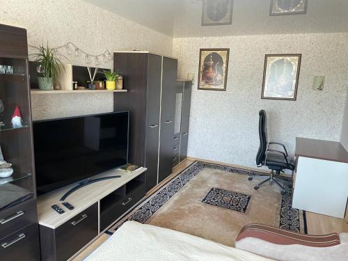 a living room with a large television and a chair at Happy Guest Apartament in Jūrmala