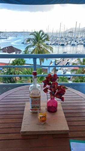 a bottle of whiskey and a vase with flowers on a table at vue panoramique Marina in Le Marin