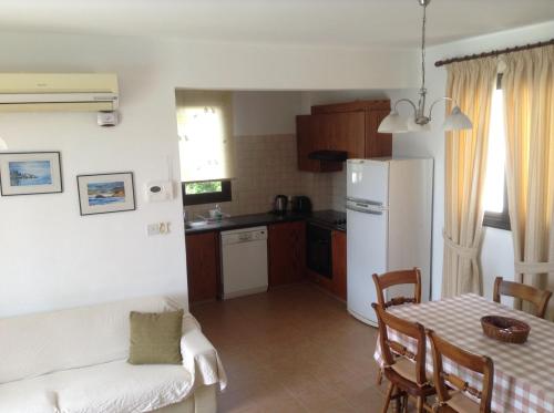a kitchen with a table and a white refrigerator at Aura Holiday Villas in Paphos