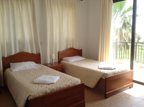 two beds in a room with a window at Aura Holiday Villas in Paphos City