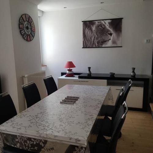 een eetkamer met een tafel met stoelen en een foto van een leeuw bij Appartement Malawo in La Flèche
