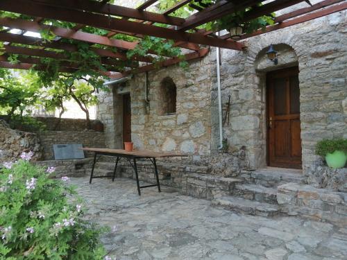 a picnic table in front of a stone building with a wooden door at ΑΝΑΒΑΤΟΣ ΕΞΟΧΙΚΗ ΚΑΤΟΙΚΙΑ in Chios