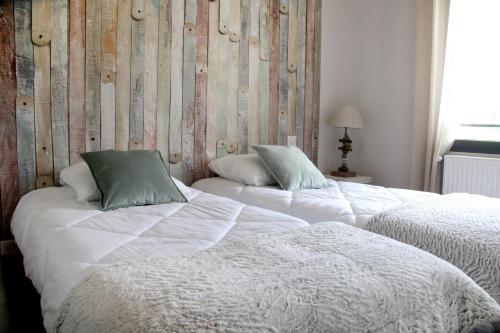 2 łóżka z białą pościelą i zielonymi poduszkami w sypialni w obiekcie Domaine des Marronniers w mieście Tourtrol