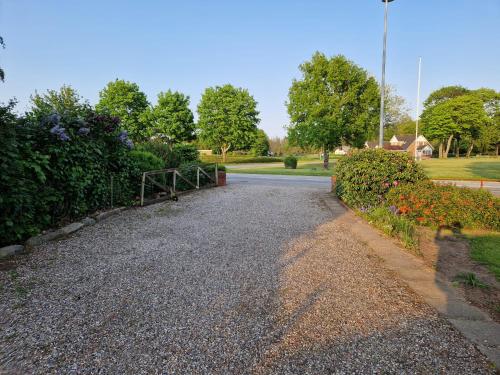 a gravel driveway with flowers and trees in a park at Guest House Rens in Bylderup-Bov