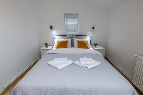 a bedroom with a white bed with two towels on it at Old Town Rooms in Novi Sad