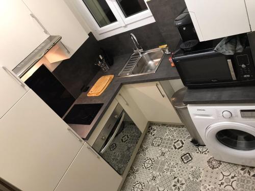 una pequeña cocina con fregadero y lavadora en Appartement 60 m², porte de Saint-Cloud, en Boulogne-Billancourt
