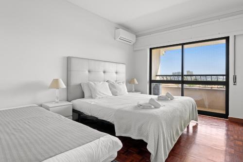 a bedroom with two beds and a large window at Cascais Terrace in Cascais