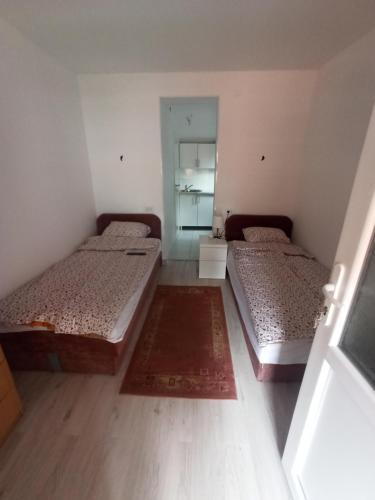 two beds in a small room with a mirror at Apartmani Lovcen in Prolom