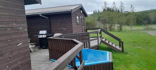 una terraza de madera con una casa y una parrilla en Ásólfsstaðir Miðtún en Ásólfsstaðir