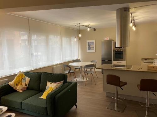 a living room with a green couch and a kitchen at El Refugio de Maman in Bilbao