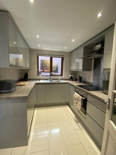 a kitchen with gray cabinets and a sink and a window at Baker House (Ormeau Road) 4Bed in Belfast