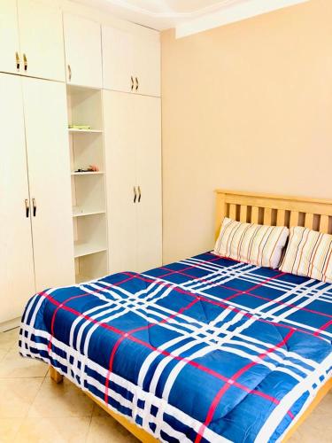 Schlafzimmer mit einem Bett mit einer blauen und weißen Bettdecke in der Unterkunft SJ Homes in Kampala