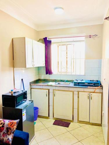een keuken met witte kasten en een raam bij SJ Homes in Kampala