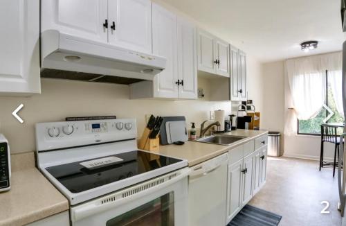 a white kitchen with a stove and a sink at Comfort & Covenience in Laurel