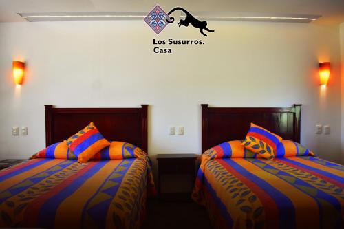 a room with two beds and a sign that reads los squares cats at Los Susurros. Casa in Palenque