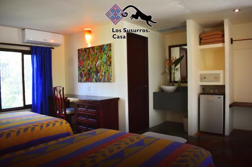 um quarto com 2 camas e uma secretária. em Los Susurros. Casa em Palenque