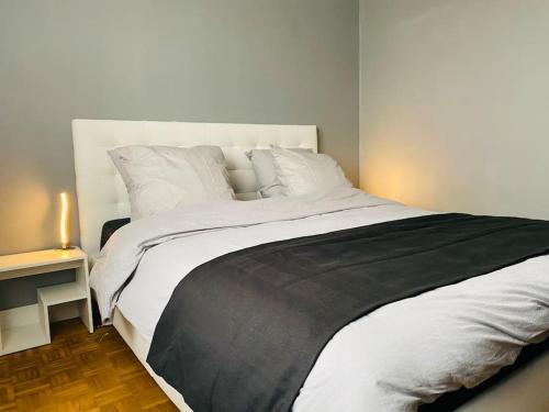 a bedroom with a large white bed and a night stand at Maison entière avec jardin - Comet Arena - Zenith in Olivet