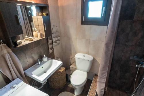 a bathroom with a white toilet and a sink at Serenity Cove, The Fox s Lair Hospitality in Agia Paraskevi