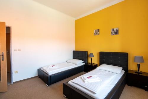 2 camas en una habitación con paredes amarillas en Hotel Prácheň, en Horažďovice
