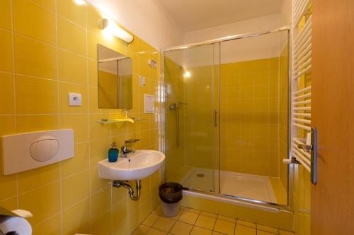 a yellow bathroom with a sink and a shower at Hotel Prácheň in Horažďovice