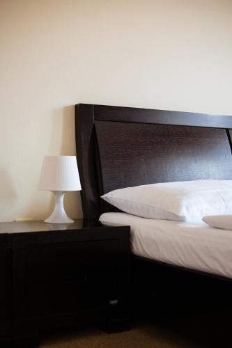a bedroom with a bed with a black headboard and a lamp at Hotel Prácheň in Horažďovice