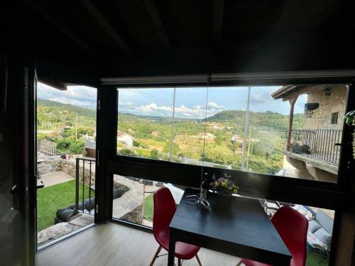 a table and chairs in a room with a large window at O Recuncho de Tibias in Pereiro de Aguiar