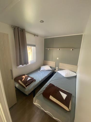 2 camas individuales en una habitación con ventana en Mobil Home 4 personnes, en Narbonne-Plage