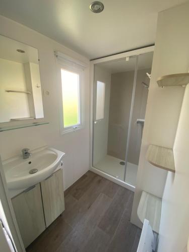 y baño blanco con lavabo y ducha. en Mobil Home 4 personnes, en Narbonne-Plage