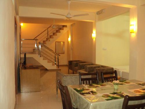 a dining room with a table and chairs and a staircase at Monalysa St Honore Apartment & Studios Grand Bay in Grand Baie