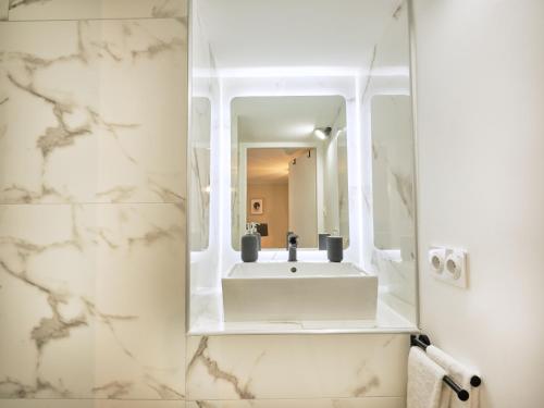La salle de bains est pourvue d'un lavabo blanc et d'un miroir. dans l'établissement Très élégant duplex, proche Gare, à Grenoble