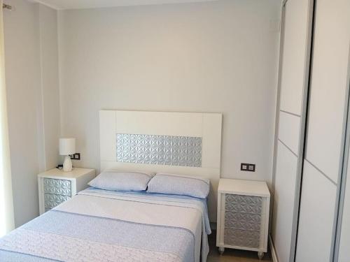 ein weißes Schlafzimmer mit 2 Betten und 2 Nachttischen in der Unterkunft Vacaciones en España in Isla Cristina
