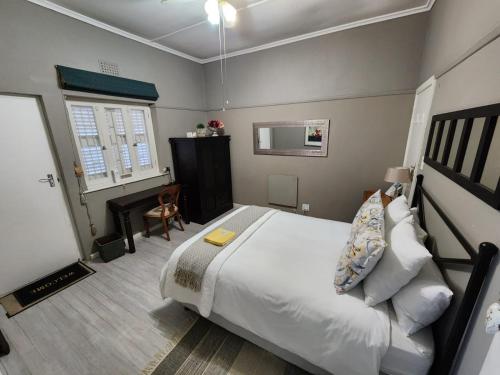 Schlafzimmer mit einem großen weißen Bett und einem Schreibtisch in der Unterkunft Peony Luxury Room with Wifi and own entrance in Stellenbosch