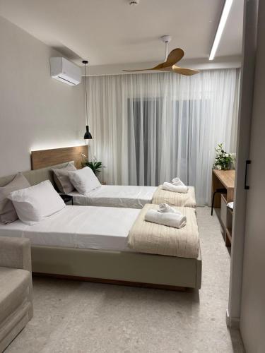a bedroom with two beds and a ceiling fan at Plagia Relax Hotel in Nea Plagia